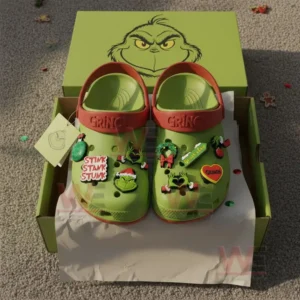 Green Grinch themed clogs with holiday charms displayed in an open box on a carpeted floor!