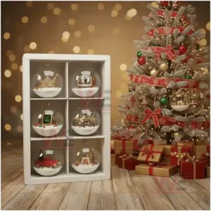 A display of glass Christmas ornaments with miniature scenes next to a decorated tree with presents on a wooden floor.