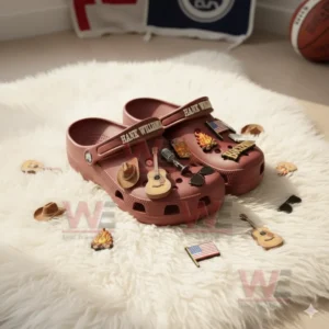 Red clogs covered with assorted country music themed charms resting on a white rug.