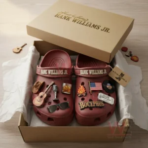 Red clogs decorated with country themed charms placed in an open box with tissue paper.