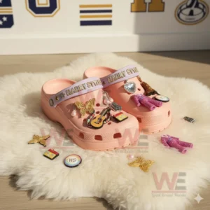 Pink Crocs decorated with Harry Styles inspired charms including glitter suit, butterfly, heart gem, and guitar shown in bright natural light on a soft rug!