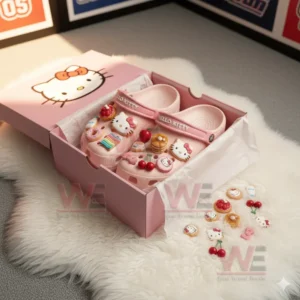 Pink clogs with assorted cute charms displayed inside an open pink box on a white rug.