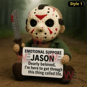 A crochet doll with a hockey mask and knife sitting on a dirt path holding a supportive message sign!