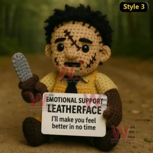 A crochet doll with a stitched face holding a small tool and a comforting message sign while sitting outdoors!