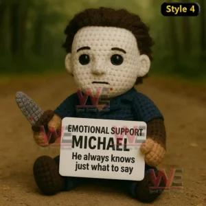 A crochet doll with a white mask and blue outfit sitting on a forest path holding a message sign of support!