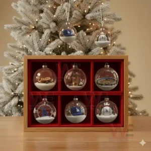 A collection of Los Angeles Dodgers Christmas ornaments displayed in a wooden box in front of a decorated Christmas tree.