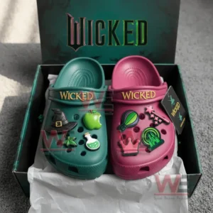 A pair of green and pink Wicked Crocs inside an open box with themed charms and branded packaging.