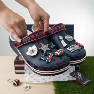Houston Texans Crocs Crocband Clogs With Charms 7 Hands holding dark blue clogs with football themed charms above a box.