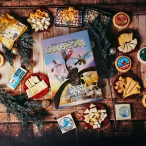 Alt text: The How to Train Your Dragon Advent Calendar surrounded by cheese, crackers, and popcorn on a wooden table.