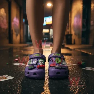 Alt text: Joker-themed crocs shoes with various colorful charms on a dark street with playing cards scattered around.