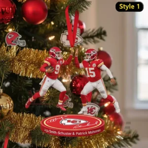 A Christmas ornament of Kansas City Chiefs players JuJu Smith-Schuster and Patrick Mahomes high-fiving, complete with team branding and a festive base.