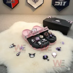 Pink and black clogs decorated with Kuromi themed charms resting on a fluffy white mat.!