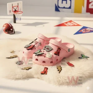 Pink clogs with various decorative charms arranged on a white furry mat in a room with sports elements in the background!