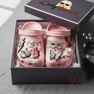 A boxed pair of pink clogs covered in colorful themed charms resting on protective padding!