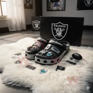 Black Las Vegas Raiders Crocs with football, stadium, and skull charms on a fluffy rug with team memorabilia.