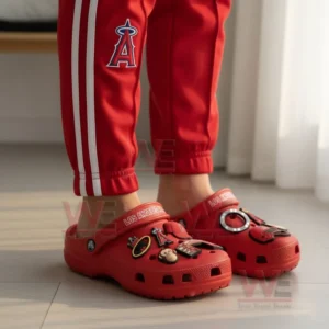 A person wearing red Los Angeles Angels Crocs decorated with charms, paired with matching red pants featuring the Angels logo.