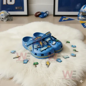 Blue Los Angeles Chargers-themed Crocs with football, team logos, and lightning bolt charms on a fluffy rug.