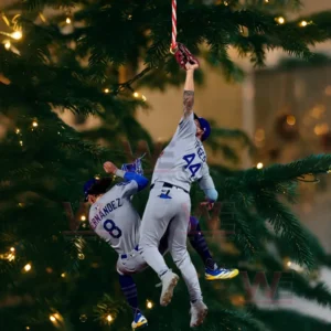 Two baseball players in grey uniforms posed as an ornament hanging from a Christmas tree branch with festive lights in the background!
