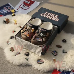 Alt text: Luke Combs-themed Crocs with various country-inspired charms inside a box on a fluffy white rug.