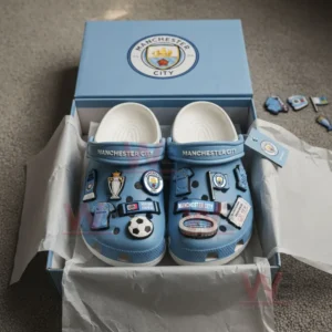 Blue Manchester City Crocs with football-related charms inside a team-branded box.