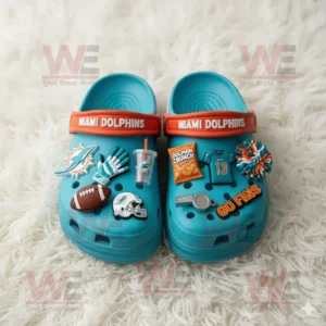 Turquoise Miami Dolphins Crocs with themed charms on a white fluffy background!