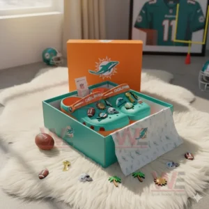 Alt text: Miami Dolphins-themed Crocs inside a box with NFL-themed charms on a fluffy white rug.