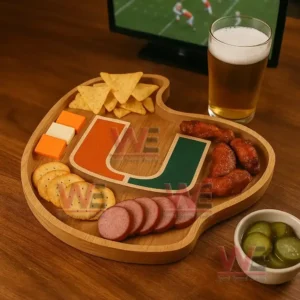 A wooden platter with a U design surrounded by assorted snacks sits near a glass of beer with a sports game on a television!