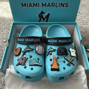 A pair of blue Miami Marlins themed clogs with multiple baseball charms arranged inside an open box.