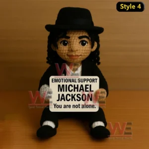Michael Jackson Emotional Support Doll 7 A crochet doll with a black hat and suit sitting on a table holding an emotional support sign!