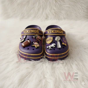 Purple Vikings clogs with assorted team themed charms placed on a white fuzzy surface!