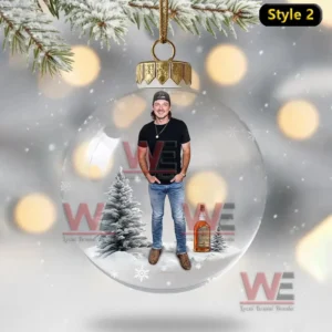 New Morgan Wallen Christmas Ornament 11 Clear ornament with a man standing beside a snowy tree and a bottle in a winter scene. ``