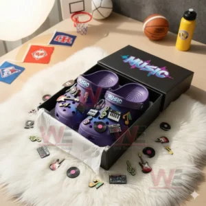 Purple clogs with music themed charms displayed in an open box with scattered accessories.!