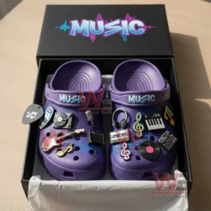 A boxed pair of purple clogs covered with detailed music themed charms.!
