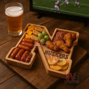 A letter shaped wooden tray filled with snacks sits on a wooden table next to a glass of beer with a sports screen in the background!