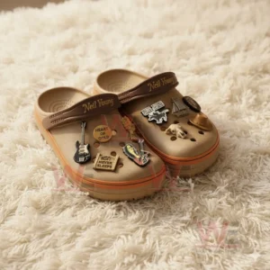 Brown Neil Young Crocs decorated with charms inspired by country music and folk rock placed on a fluffy beige rug!