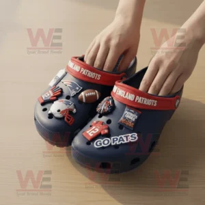 New England Patriots Crocs with themed charms being held over a wooden table!