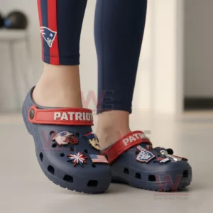 Person wearing navy Patriots clogs with various decorative charms!