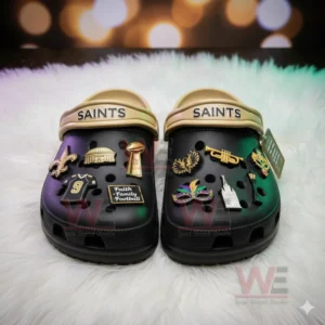 Black Saints clogs with various gold and colorful charms displayed on a white furry surface!