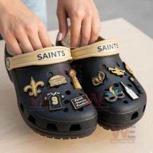 Person holding black Saints clogs adorned with assorted themed charms!