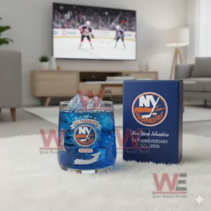 New York Islanders whiskey glass with blue drink and ice, set on the floor while a hockey game plays on the TV in the background.