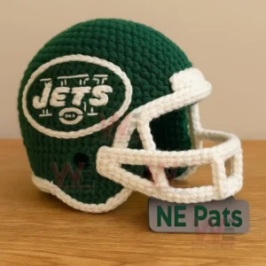 Green crocheted football helmet with white stitched details and a white yarn face guard on a wooden surface.