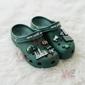 Green Jets clogs with multiple themed charms displayed on a white furry surface!