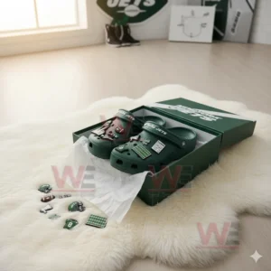 Green Jets clogs on a white fur surface with scattered themed charms!