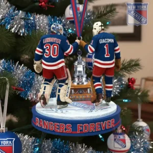 Two hockey goalie figures stand on a round team themed ornament with a trophy between them hanging from a Christmas tree decorated with blue red and silver ornaments!