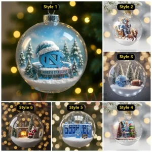 A Christmas ornament with the North Carolina Tar Heels logo, set against a snowy winter scene with Christmas trees and snowflakes.