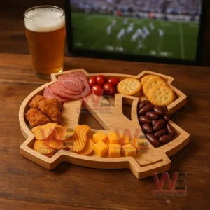 An emblem shaped wooden tray filled with assorted snacks sits on a wooden table next to a glass of beer with a sports screen in the background!