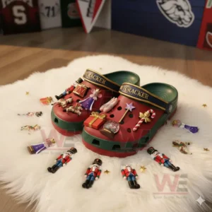 Nutcracker themed red and green clogs decorated with Christmas charms on a fluffy white mat.!
