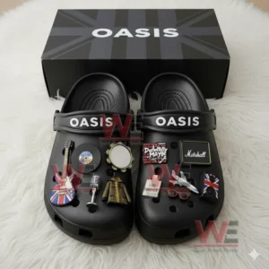 A black pair of Oasis themed Crocs decorated with music and British flag charms placed before a matching logo box.