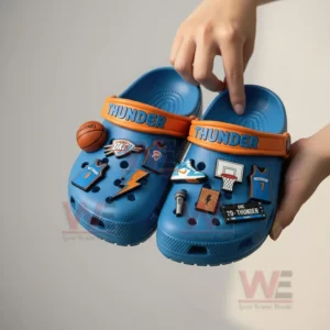 Person holding Oklahoma City Thunder-themed Crocs with basketball-related charms.