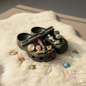 Black OneRepublic Crocs with artistic and gold themed charms displayed on a white fur rug in sunlight!
